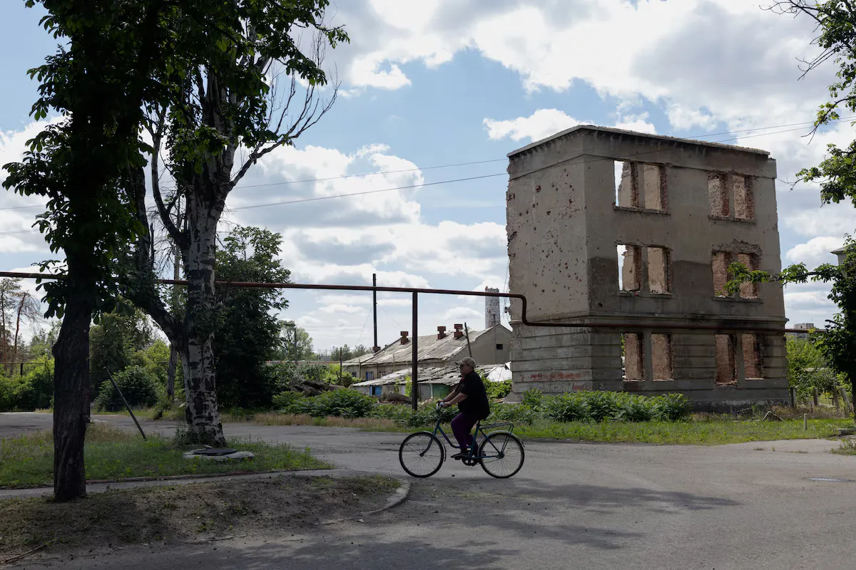 Чоловік проїжджає повз пошкоджений житловий будинок у місті Лиман, поблизу лінії фронту в Донецькій області.